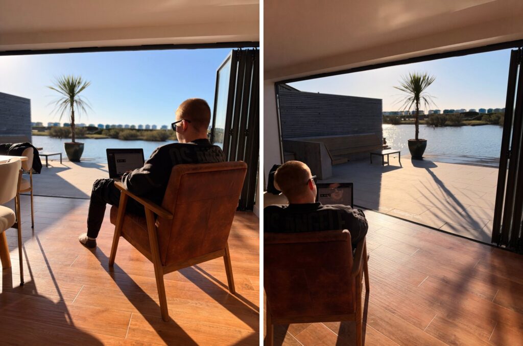 Travis working from a leather armchair by open bi-fold doors overlooking the water on the first morning