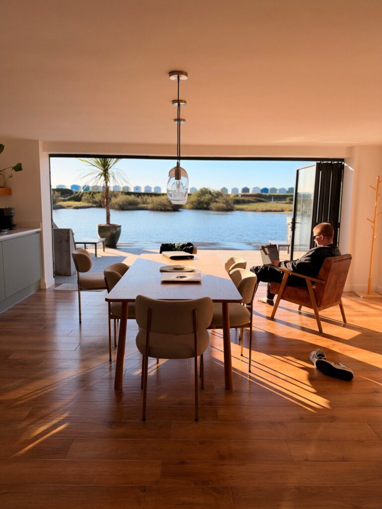 Open-plan living room of the Search Theory team Airbnb with bi-fold doors open onto the water
